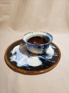 a blue and white bowl sitting on top of a saucer filled with brown liquid