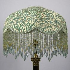 a table lamp with a green and white shade on it's base, hanging from the ceiling