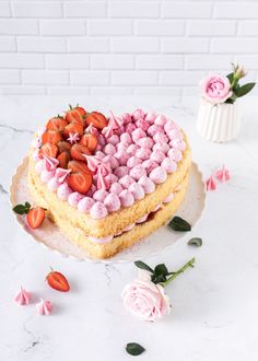 a heart shaped cake with strawberries on top and pink icing around the edges