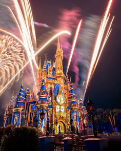 fireworks light up the night sky in front of disney's castle at disneyland world