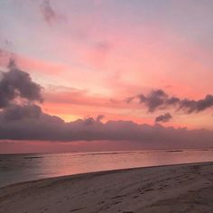 the sun is setting at the beach with clouds in the sky