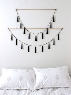 a white bed with black tassels hanging on the wall