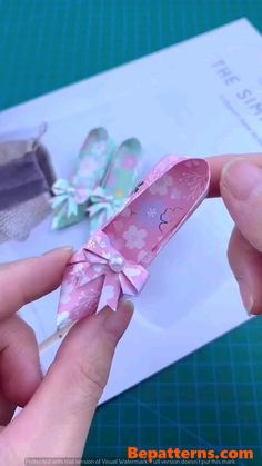 a person is holding an origami shoe with a bow on the front and side