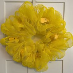 a yellow mesh wreath hanging on the front door with two little buttons in it's center