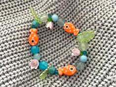 a close up of a bracelet made with beads and flowers on a knitted surface