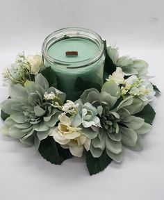 a candle surrounded by flowers and greenery