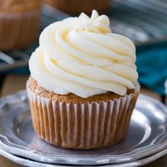 a cupcake with white frosting sitting on a plate