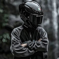 a man wearing a motorcycle helmet standing with his arms crossed