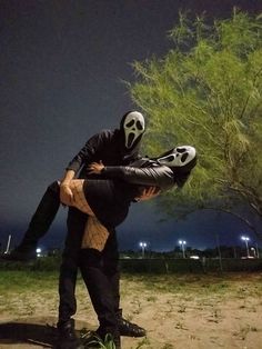 a man in a skeleton mask is holding a woman