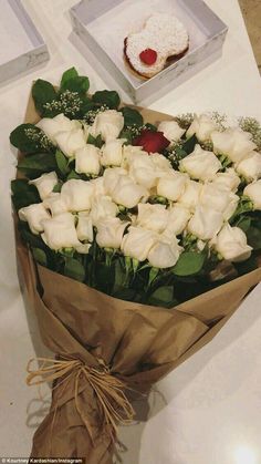 a bouquet of white roses sitting on top of a table next to an open box