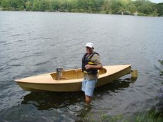 a man standing in the water next to a small boat with a cooler on it