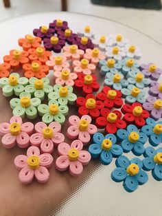 there are many different colors of buttons on the table with each one being held by someone's hand