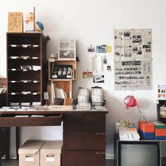 a desk with many books and papers on it in front of a book shelf filled with files