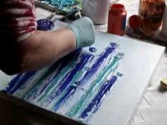 someone is painting on paper with blue and green paint