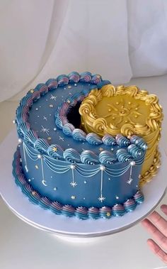 there is a blue and gold cake with stars on the top, sitting on a white plate