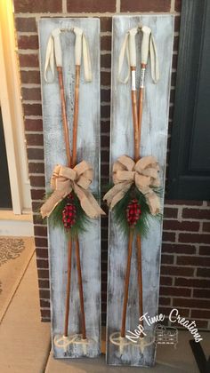 two wooden skis decorated with bows and pine cones are sitting in front of a brick wall