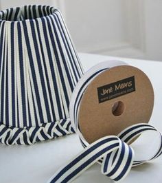 a roll of blue and white striped ribbon next to a lamp shade on a table