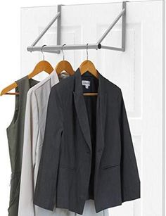 three suits hanging on a coat rack in front of a white door