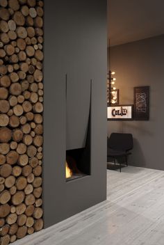 a room with wood stacked on the wall and a fire place in the corner that is built into the floor