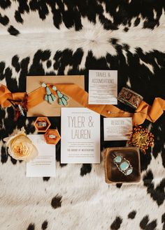 the wedding stationery is laid out on a cowhide rug with flowers and jewelry