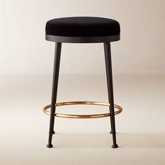 a black stool with a gold ring around the foot rest and back rests on a white background