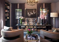 a living room filled with furniture and a chandelier hanging from the ceiling over a table