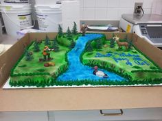 a birthday cake in the shape of a river and forest scene with animals on it