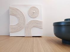 a white sculpture sitting on top of a wooden floor next to a bowl and vase