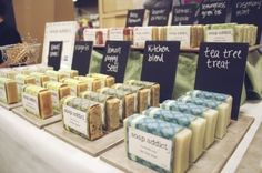 several different types of soaps on display at a market stall with price signs in front of them