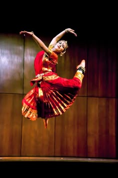 a woman in a red and gold dress is doing a dance move on the stage