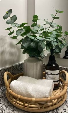 a bamboo basket with towels and soaps in it on a bathroom counter next to a potted plant