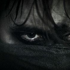 the eyes of a person with long hair and black cloth on their face are shown