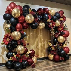 the balloon arch is decorated with black, red and gold balloons