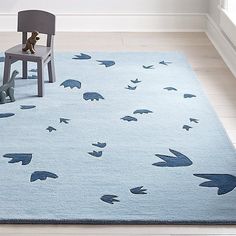 a child's room with a blue rug, chair and teddy bear on the floor