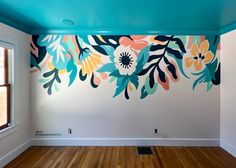 an empty room with painted flowers on the wall and wood flooring in front of it