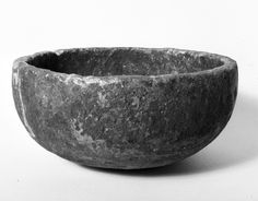 a black and white photo of a stone bowl on a plain surface with no background