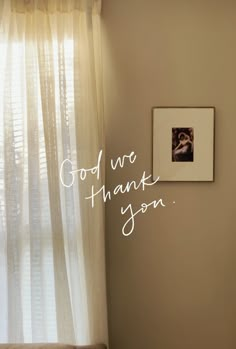 a photo hanging on the wall next to a window with words written in white ink