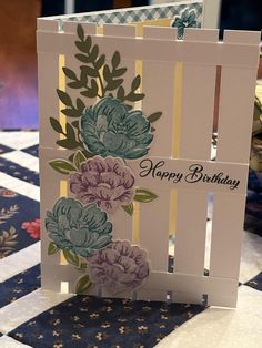 a birthday card with flowers on it sitting on top of a checkered tablecloth