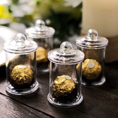 four glass jars with gold foiled chocolates in them