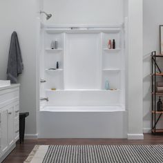 a bathroom with white walls and flooring, including a bathtub that has shelves on the wall