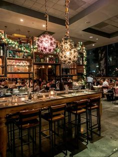 people sitting at tables in a restaurant with chandeliers hanging from the ceiling