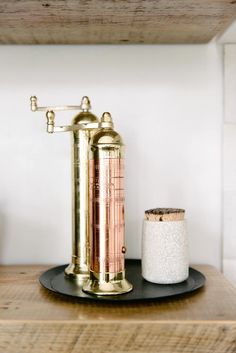 an old fashioned copper faucet sitting on top of a wooden shelf next to a salt and pepper shaker