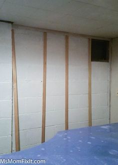 an unfinished room with white walls and blue sheets on the floor, next to a wall mounted air conditioner