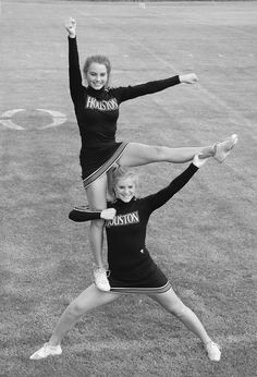 two cheerleaders are doing tricks on the field with their hands in the air