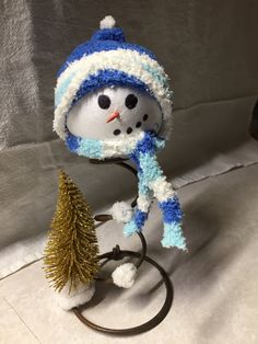 a snowman with a blue and white hat on top of a small christmas tree