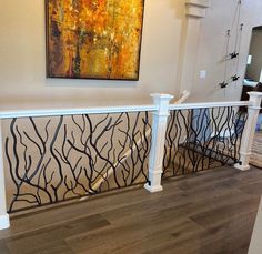 a painting hanging on the wall next to a banister in a living room with wood flooring