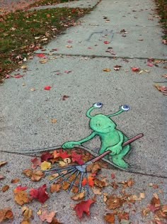 a street scene with leaves on the ground and a drawing of a frog holding a broom