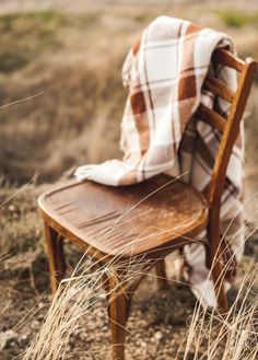 a chair with a blanket on top of it sitting in the middle of a field