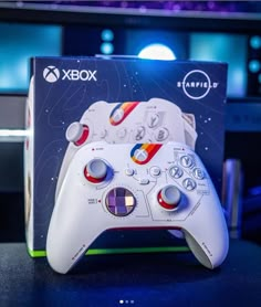 a white controller sitting on top of a table in front of a box with the game logo