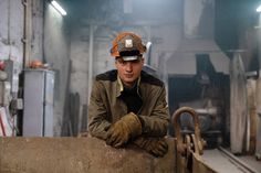 a man wearing a hard hat and working gloves in a factory by jording for stocks